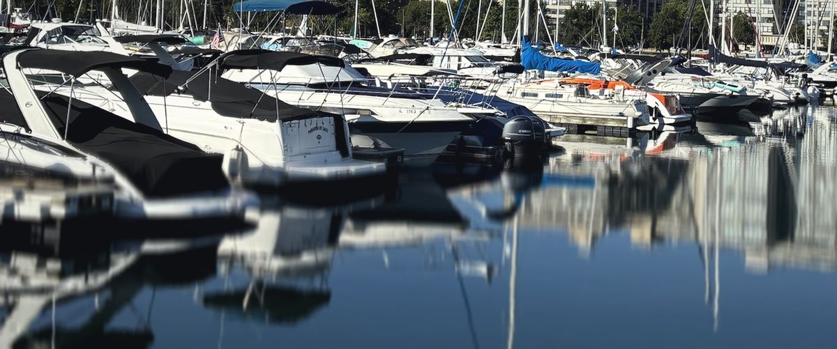 Calm marina at morning, boats and their reflections on flat water